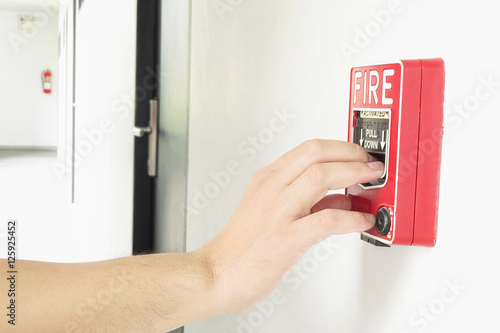 Man is reaching his hand to push fire alarm hand station