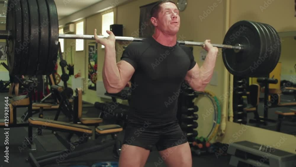 Sportsman perform exercises a squats with a barbell at the training in the gym Sportsman perform exercises a squats with a barbell at the training in the gym