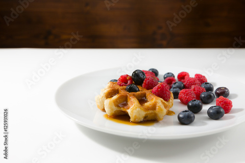 Waffles with fresh ripe berries over a white plate