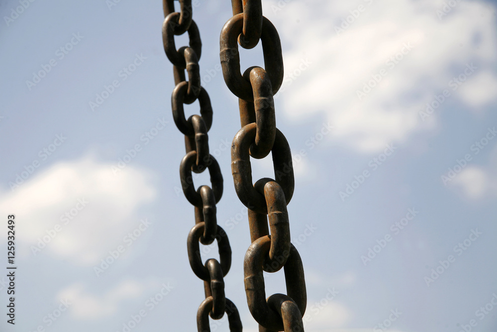 Old iron rusty chains in hanging in the air against blue sky Old iron rusty chains in hanging in the air against blue sky