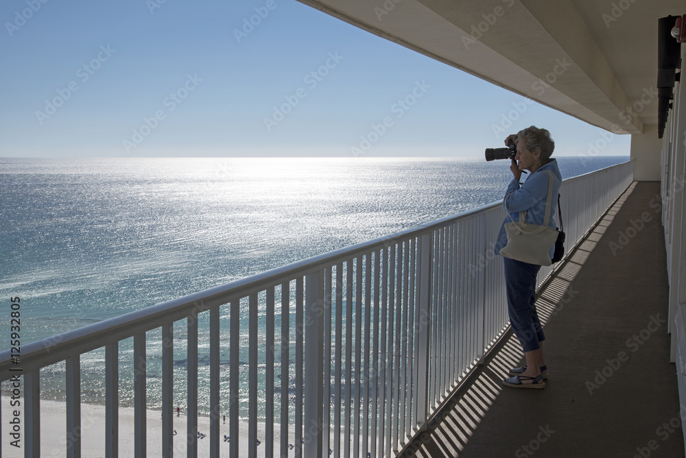 Gulf Coast Florida USA - October 2010 - Woman taking a photo of the Gulf coastline from a highrise balcony Gulf Coast Florida USA - October 2010 - Woman taking a photo of the Gulf coastline from a highrise balcony