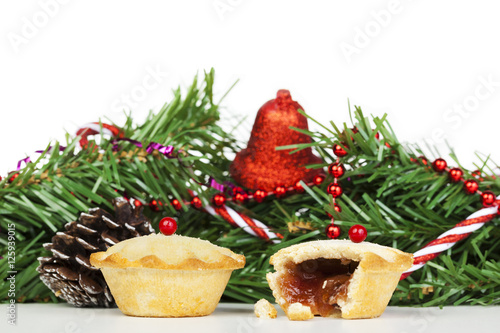 Two fresh mince pies in front of christmas decorations