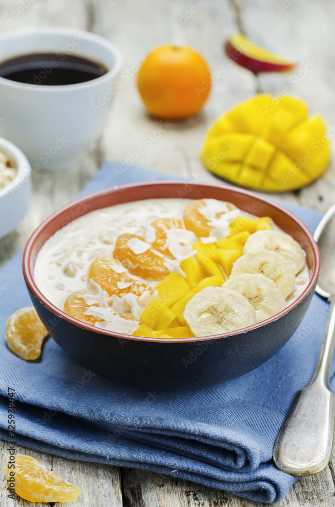 Oatmeal with mango, banana, tangerine oranges and coconut flakes Oatmeal with mango, banana, tangerine oranges and coconut flakes