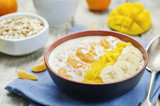 Oatmeal with mango, banana, tangerine oranges and coconut flakes