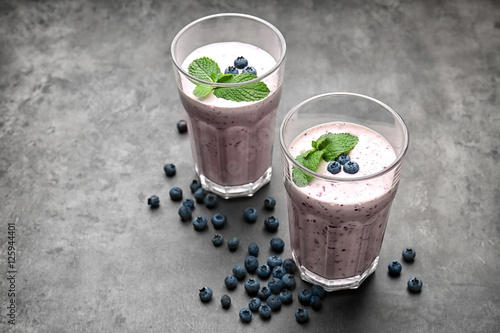 Two glasses of tasty smoothie with blueberries on grey table