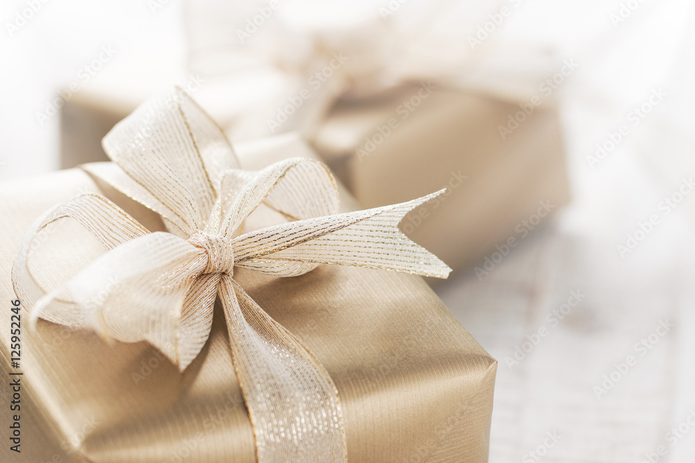 Golden gift boxes with beautiful ribbon and bow on a bright shiny background, holiday concept, horizontal with copy space Golden gift boxes with beautiful ribbon and bow on a bright shiny background, holiday concept, horizontal with copy space