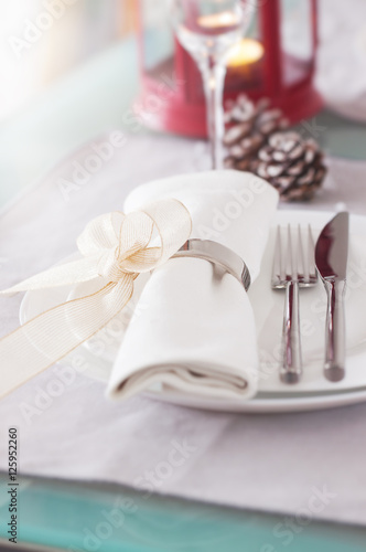 Elegant decorated Christmas table setting with modern cutlery, napkin, bow and christmas decorations. Christmas menu concept, closeup