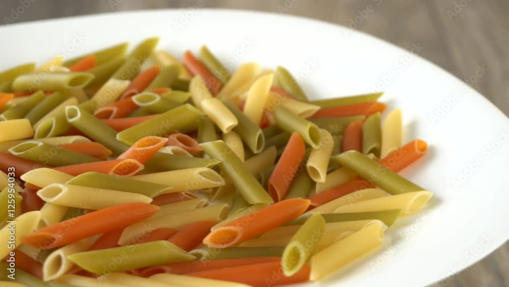 Colorful raw pasta rotating on a white plate. Seamless loopable. Prores 4K. Colorful raw pasta rotating on a white plate. Seamless loopable. Prores 4K.