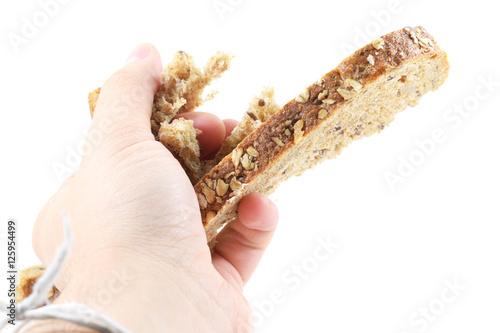 Man's hand crushing a slice of whole wheat bread