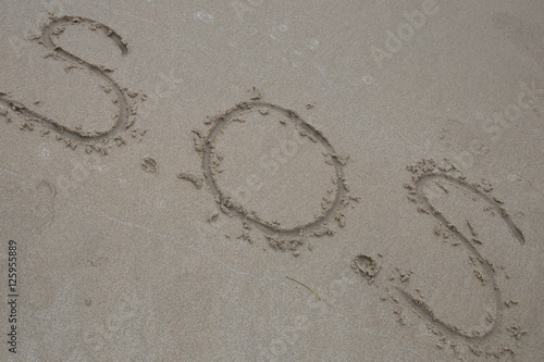S.O.S. handwritten in sand for natural  symbol tourism or conceptual designs