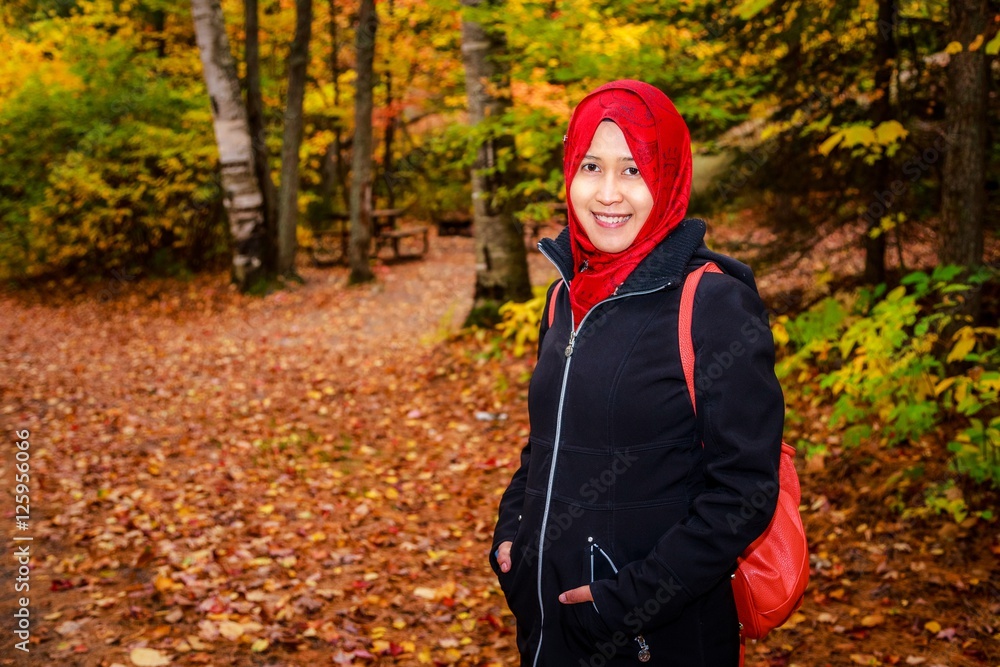 Muslim woman in North America during autumn with colorful maple leaf as background Muslim woman in North America during autumn with colorful maple leaf as background