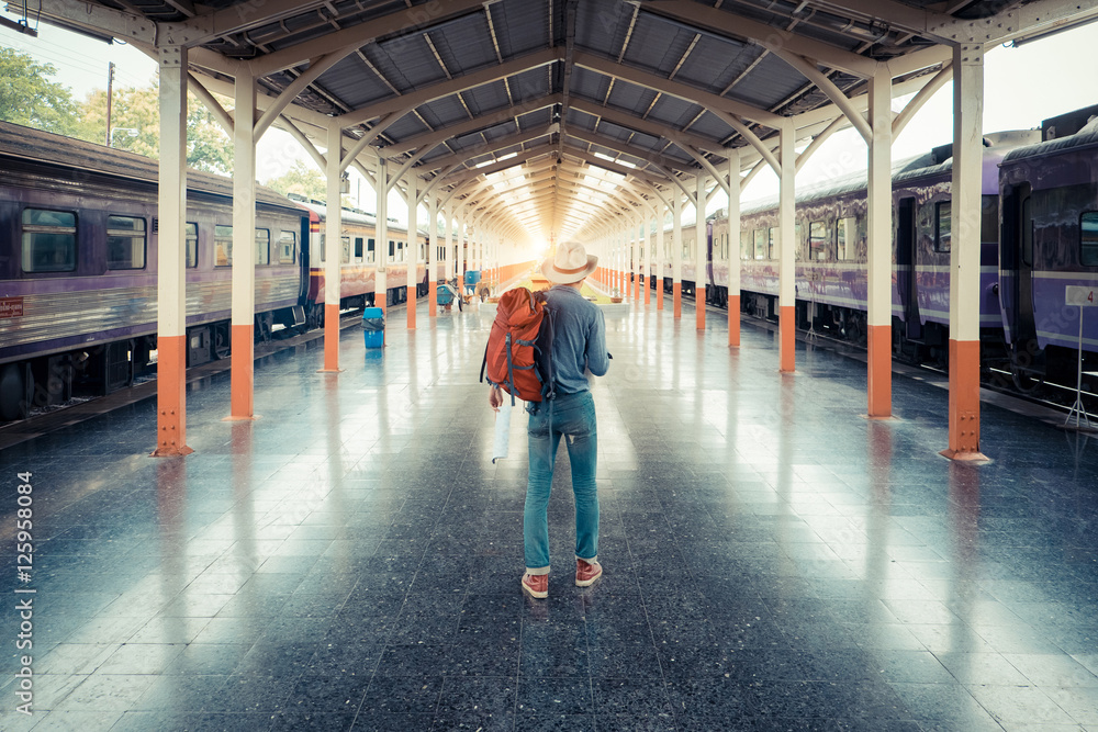 Young man traveler at train station with map choose where to tra Young man traveler at train station with map choose where to tra