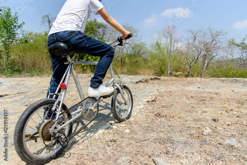 Little boy ride bicycle on the rock road.