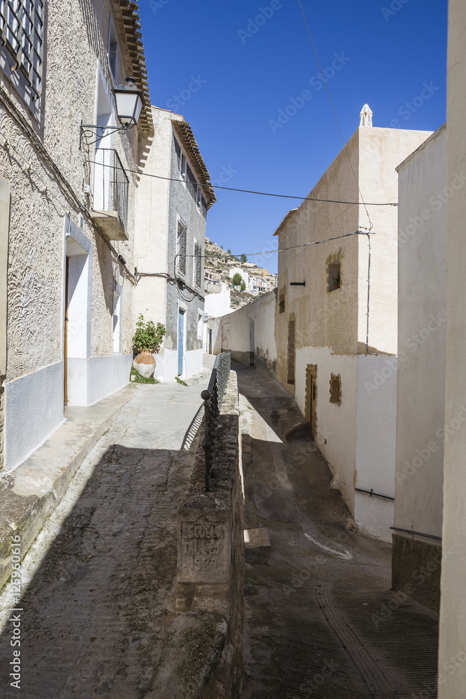 Narrow street with white painted houses, typical of this town, t