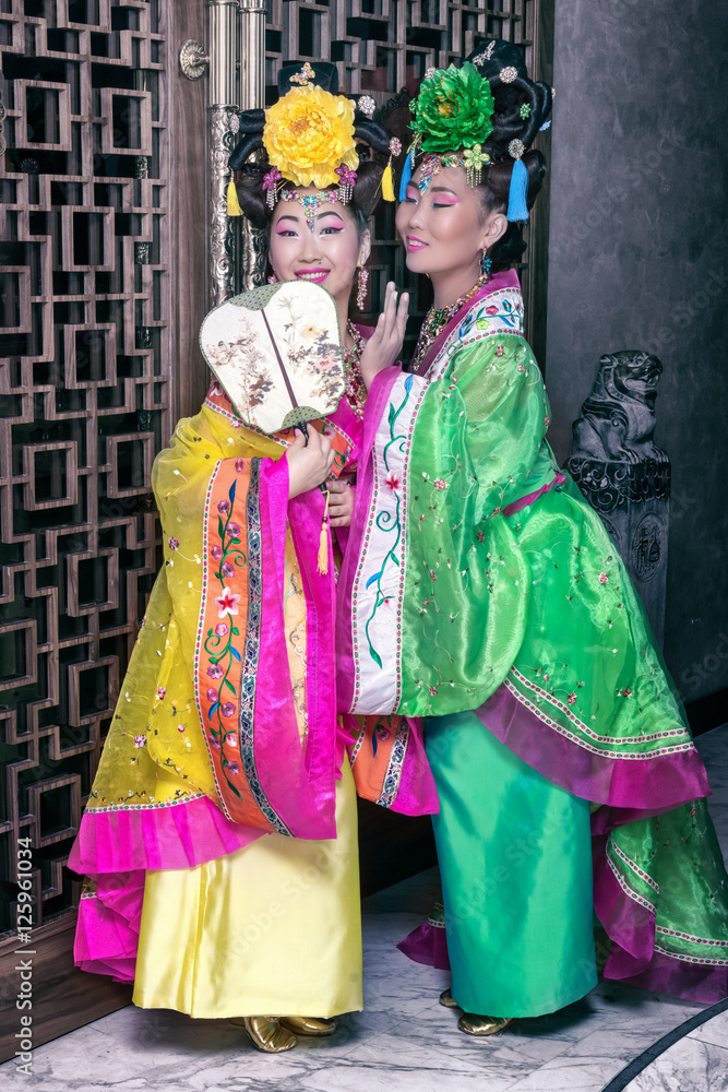 two geishas whispering in traditional Chinese national dresses
