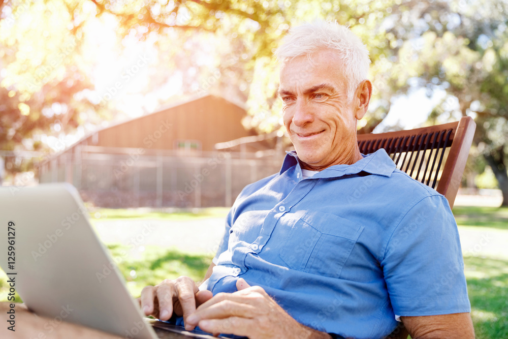 Senior man with notebook sitting in the park Senior man with notebook sitting in the park