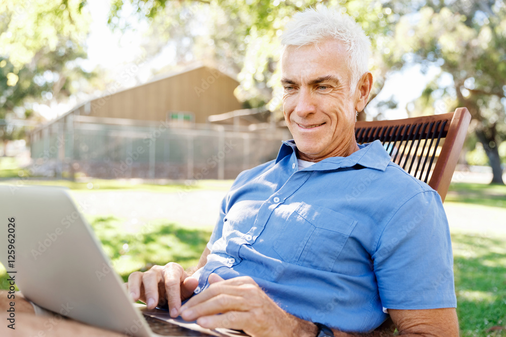 Senior man with notebook sitting in the park Senior man with notebook sitting in the park
