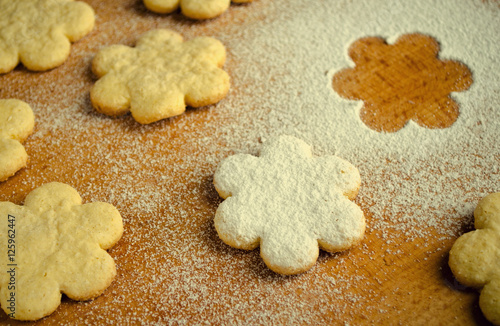 Homemade shortbread flower shape cookies with sugar powder on wooden table