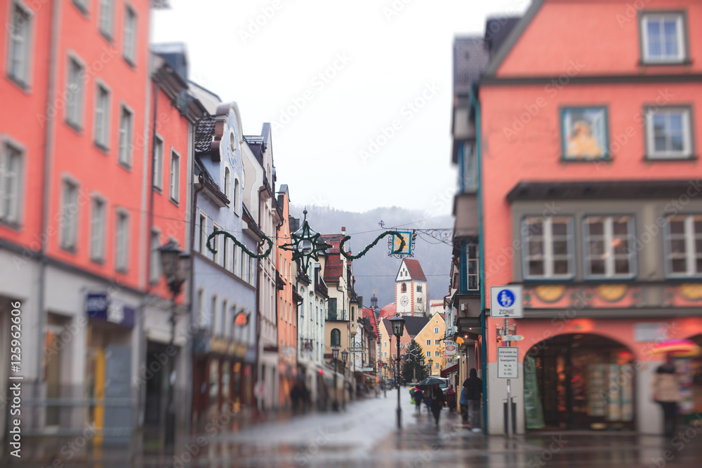 Beautiful vibrant multicolored downtown picture of street in Fussen, Bayern, Bavaria, Germany, with tourists and people walking near shop-windows and restaurants, houses in bavarian style