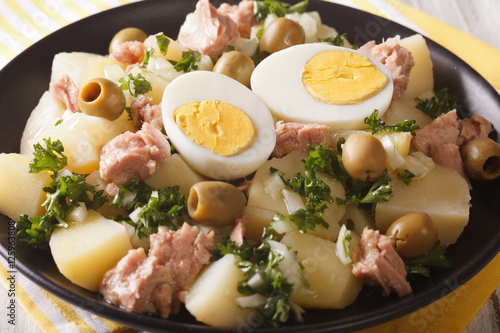 Spanish salad Patatas Alinadas of boiled potatoes with tuna, egg and olives close-up. horizontal