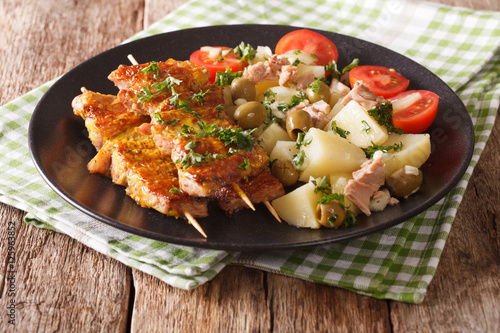 Spanish kebab Pinchos Morunos and salad Patatas Alinadas close-up. Horizontal photo