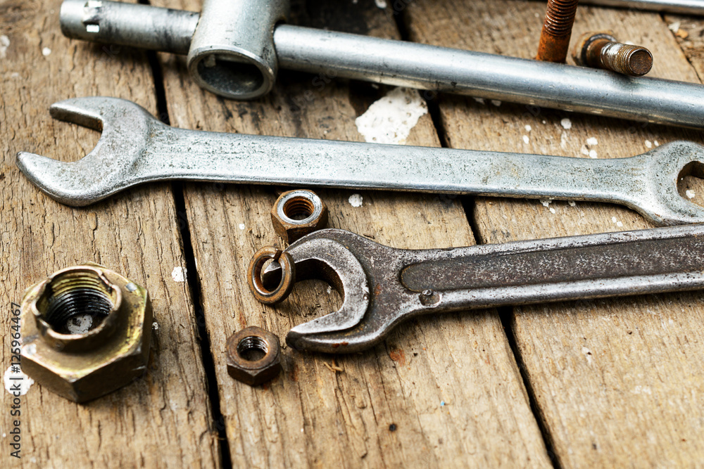 On weathered old wooden surface lie the , oily wrenches. On weathered old wooden surface lie the , oily wrenches.