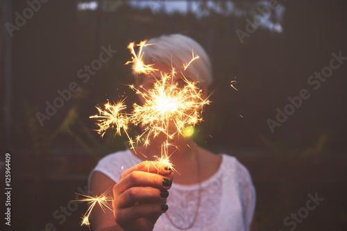 Woman hand holding sparkler outdoors photo