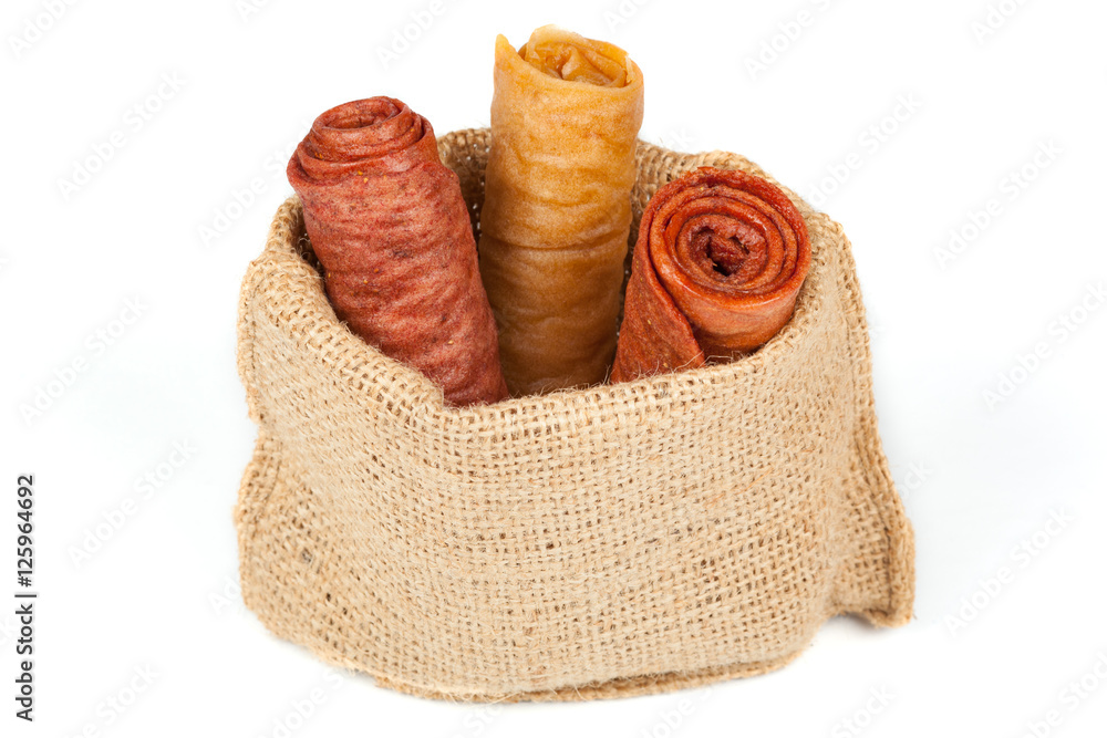 Candied fruit twisted a roll in the linen bag isolated on white background. Homemade sweetness of dried fruit.
