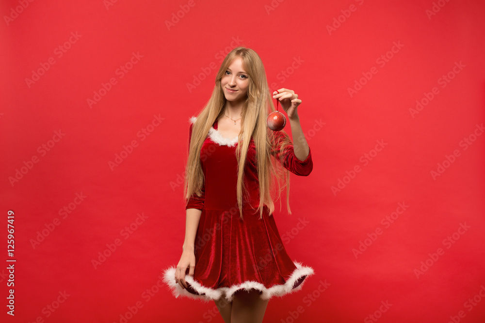 santa girl posing on a red background with the toy. santa girl posing on a red background with the toy.