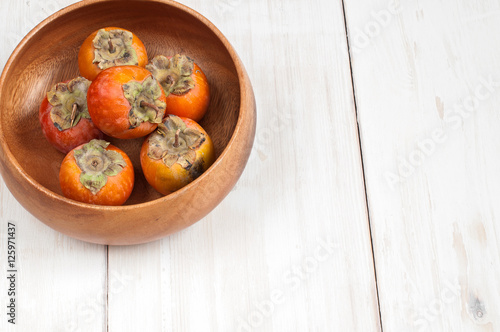 Ripe Persimmon fruit in a wooden bowl