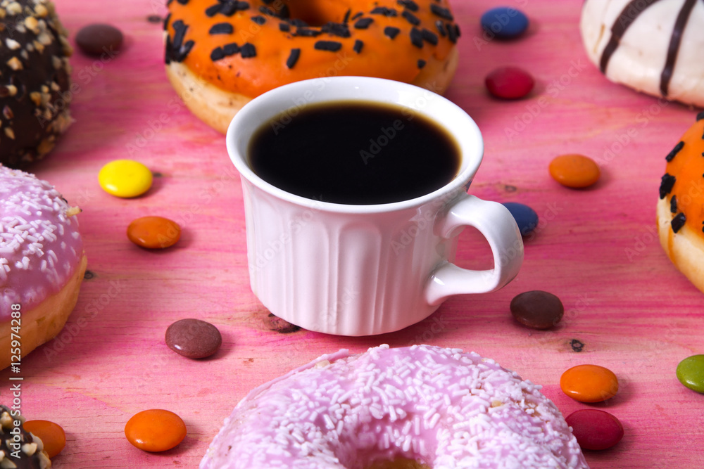 Cup of coffee with donuts and smarties on pink background Cup of coffee with donuts and smarties on pink background