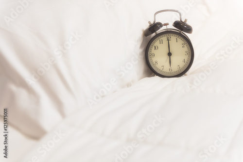 Alarm clock set on white sheet with morning light awake