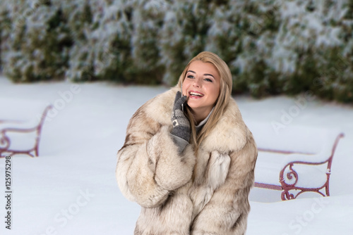 portrait of the young woman in a fur   in the snow-covered park photo