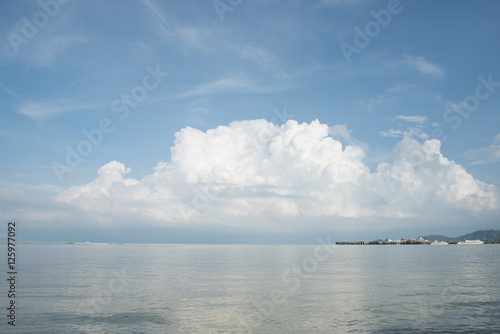 Summer seascape with green island and blue sky background