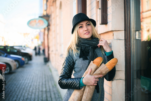 Young beautiful woman with a loaf of bread in her hands in autumn on the street.