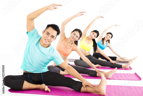 smiling young fit group stretching in gym