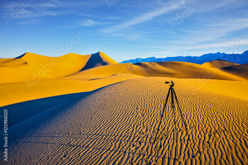 Tripod with camera stands on a sand dune