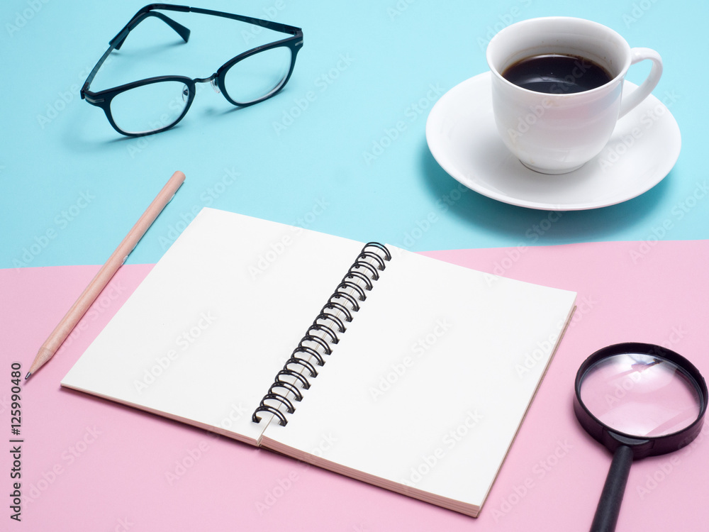 Top view of colorful cup of coffee , notebook , glasses on blue and pink background Top view of colorful cup of coffee , notebook , glasses on blue and pink background