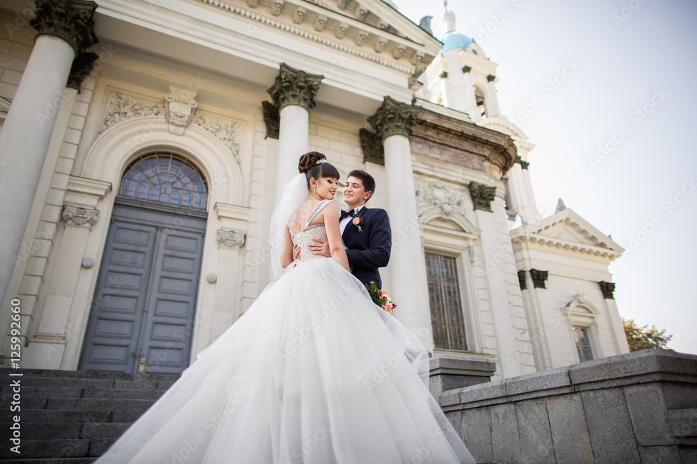 Obraz premium Wedding bride and groom, happy young couple hugging near the place of wedding ceremony