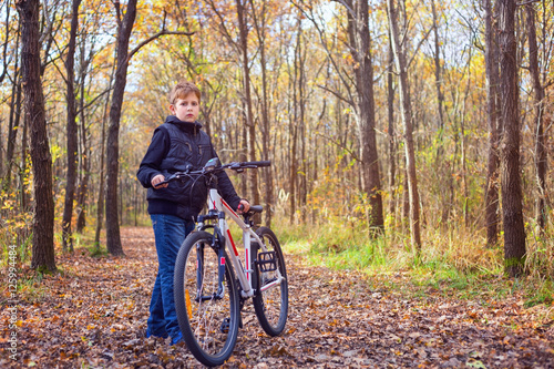 Little kid posing with his bicycle in the forest