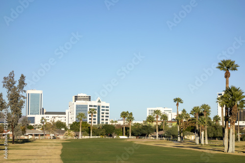 View at Phoenix Downtown from Encanto Park green golf course lawns, Arizona; Copy space in clear blue sky photo