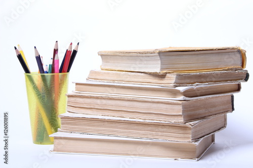 stack of old books. pencils in a glass