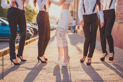 Beautiful legs of young girlfriends stylishly dressed in suits at hen-party.