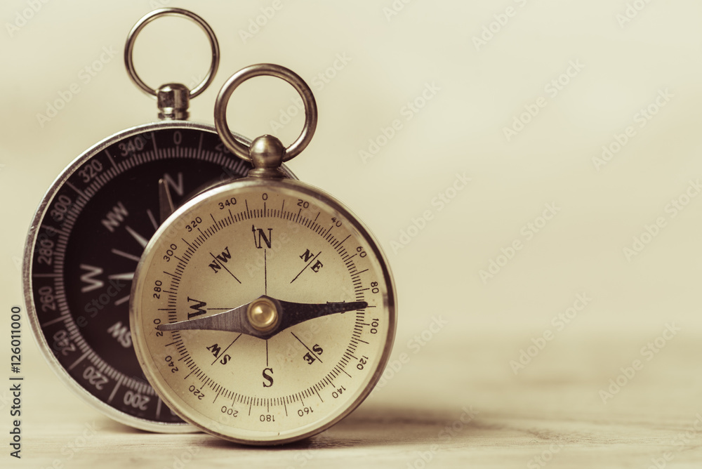 Two compass white and black on a beige background