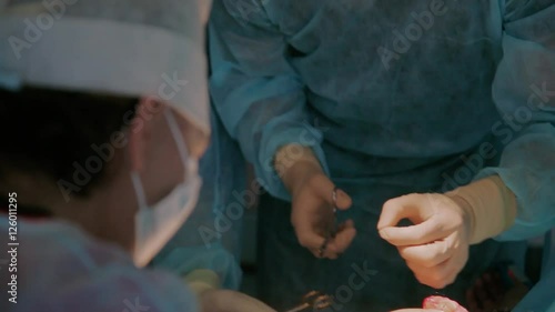 Team of surgeons in operating room in process of completing the reimplantation surgery photo