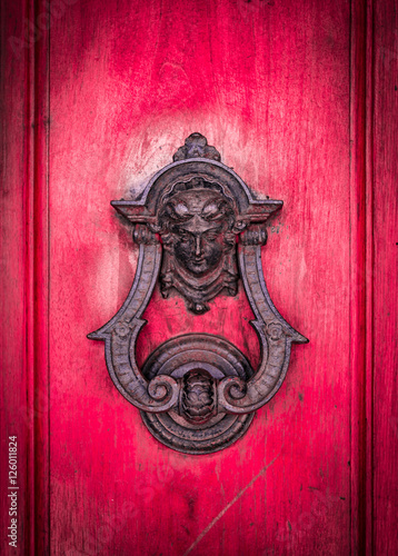 Door knoker on an old red wooden door.