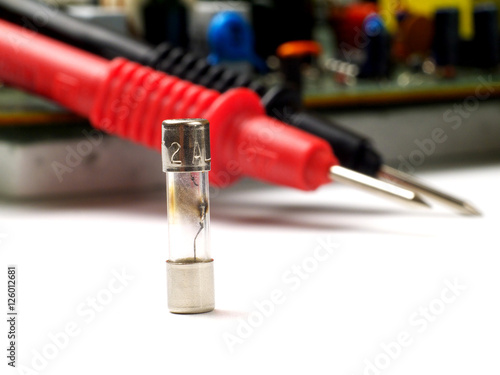a blown fuse in front of circuit board and multimeter propbes, macro, shallow depth of field