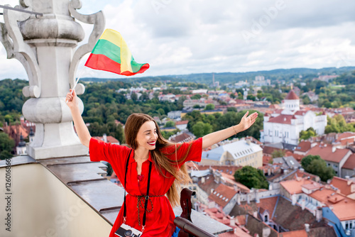 Young female tourist with photo camera and flag enjoying great view on the old town on the tower in Vilnius. Woman having happy vacations in lithuania photo