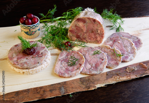 Homemade headcheese with dill and cranberries on a wooden board