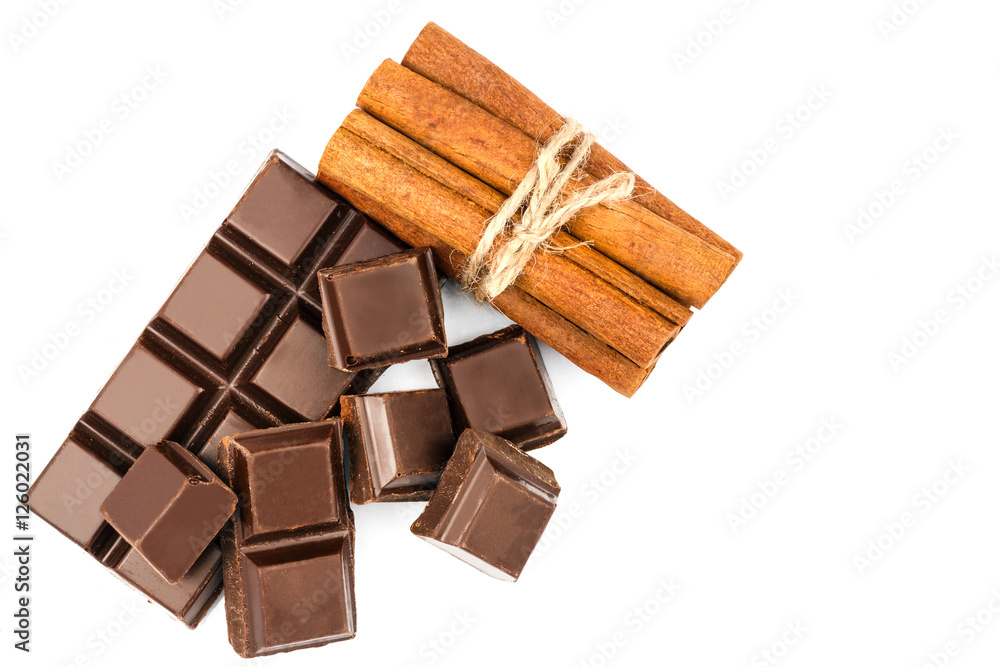 Dark chocolate bar, cubes and cinnamon sticks isolated on white background, top view. Dark chocolate bar, cubes and cinnamon sticks isolated on white background, top view.